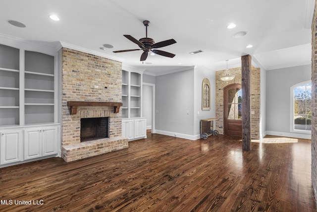 unfurnished living room featuring built in features, dark hardwood / wood-style flooring, ornamental molding, ceiling fan, and a brick fireplace