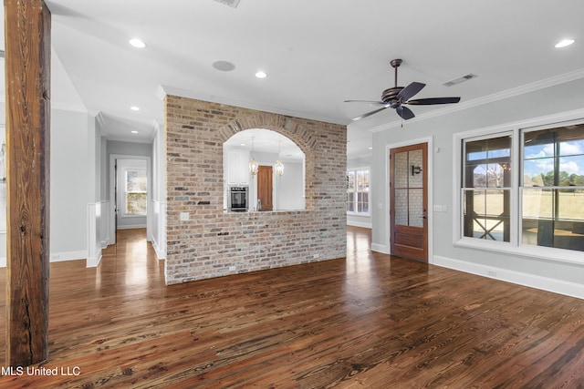 unfurnished living room featuring crown molding, dark hardwood / wood-style floors, ceiling fan, and brick wall