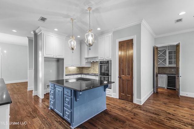 kitchen with appliances with stainless steel finishes, pendant lighting, tasteful backsplash, white cabinets, and blue cabinetry