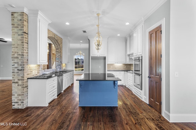 kitchen featuring appliances with stainless steel finishes, decorative light fixtures, white cabinetry, decorative backsplash, and an inviting chandelier