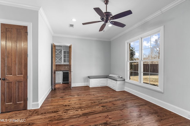 unfurnished room with wine cooler, crown molding, a wealth of natural light, and dark hardwood / wood-style floors