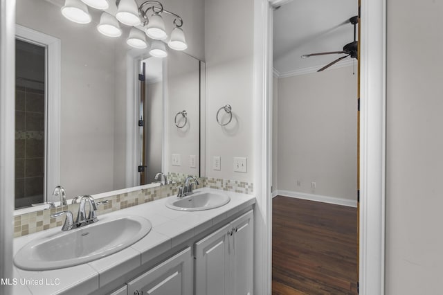 bathroom with crown molding, vanity, hardwood / wood-style flooring, ceiling fan, and decorative backsplash