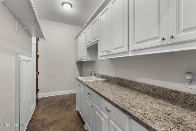 kitchen with light stone counters, sink, and white cabinets