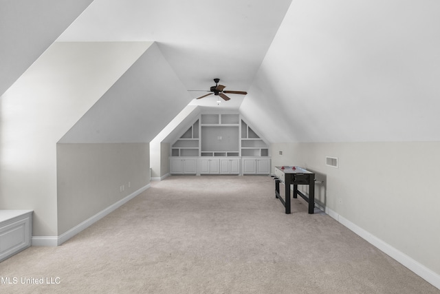 additional living space with light carpet, built in shelves, lofted ceiling, and ceiling fan