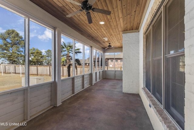 unfurnished sunroom with ceiling fan, wood ceiling, and a healthy amount of sunlight