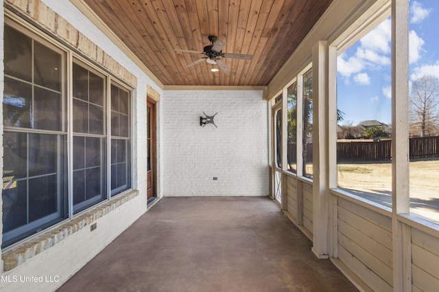 unfurnished sunroom featuring wood ceiling, a wealth of natural light, and ceiling fan