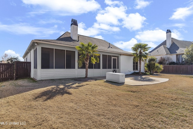 rear view of house with a sunroom, a lawn, and a patio area