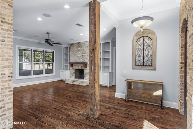 unfurnished living room with crown molding, a fireplace, built in shelves, and dark wood-type flooring