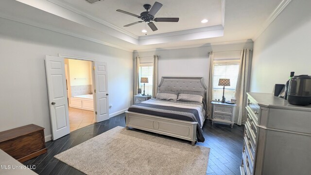 bedroom with ceiling fan, dark hardwood / wood-style flooring, a tray ceiling, crown molding, and ensuite bath