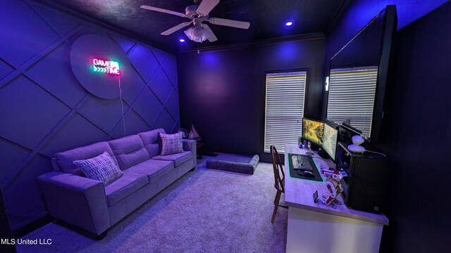 carpeted cinema room with ceiling fan and crown molding