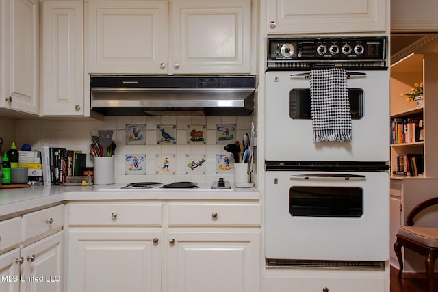 kitchen featuring white cabinets, under cabinet range hood, white appliances, and decorative backsplash