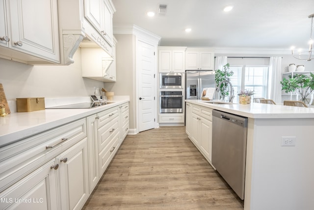 kitchen featuring white cabinetry, light wood-type flooring, stainless steel appliances, sink, and decorative light fixtures