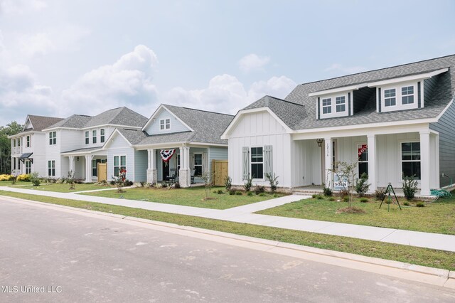 12105 Creole Way, Gulfport, MS 39503 - view of front facade featuring board and batten siding, a shingled roof, a front yard, and covered porch