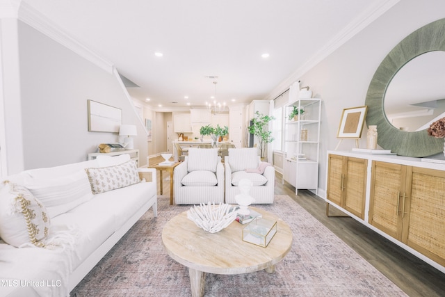 living room featuring an inviting chandelier, ornamental molding, and dark wood-type flooring