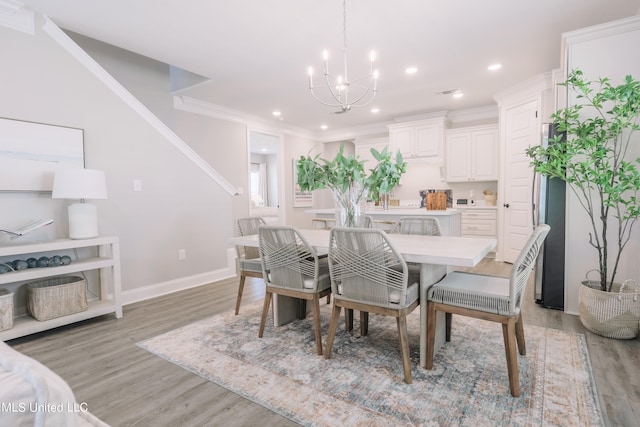 dining space featuring crown molding, a notable chandelier, and light hardwood / wood-style floors