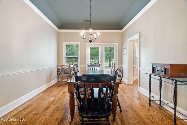 dining area featuring a chandelier, wood finished floors, ornamental molding, and baseboards