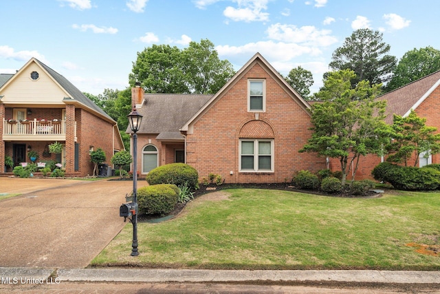 view of front of property with brick siding, a front lawn, and a chimney