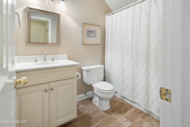 bathroom featuring toilet, vanity, and curtained shower