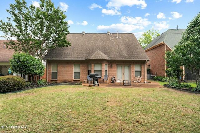 back of property featuring brick siding, a patio, a yard, and a shingled roof