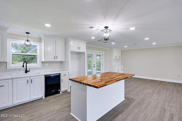 kitchen featuring wood counters, sink, dishwasher, white cabinetry, and hanging light fixtures