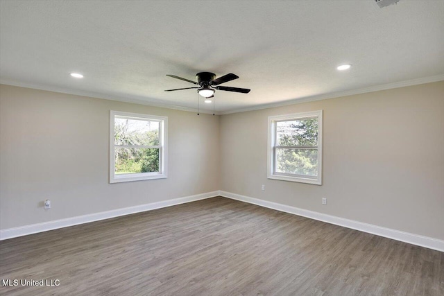 empty room featuring dark hardwood / wood-style floors, a wealth of natural light, ornamental molding, and ceiling fan