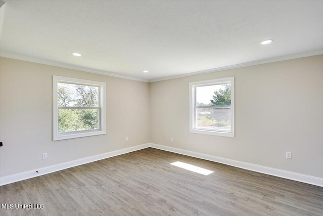 spare room with hardwood / wood-style flooring, plenty of natural light, and crown molding