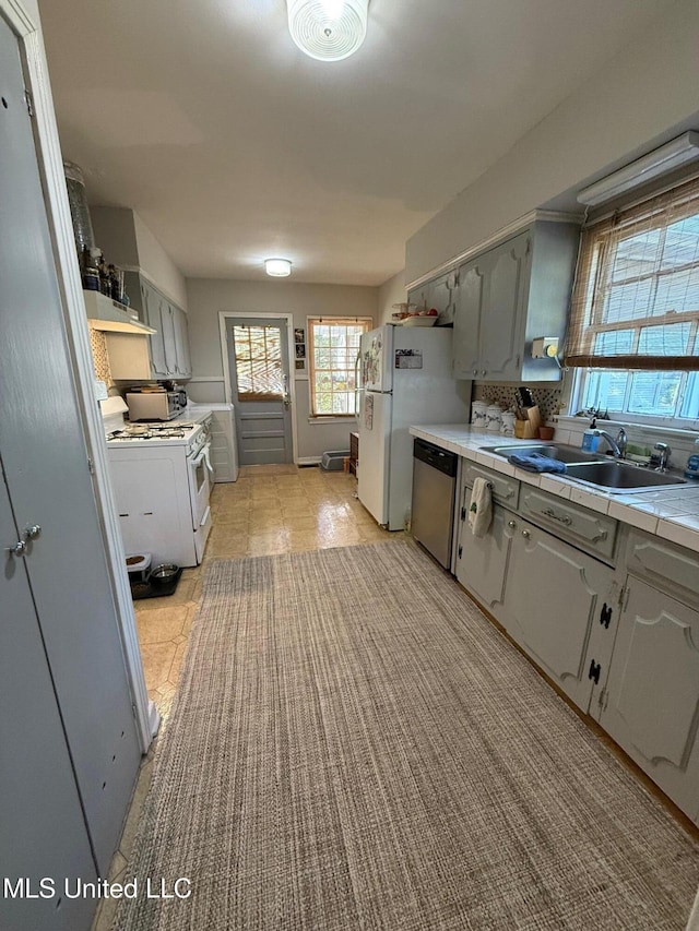 kitchen with gray cabinetry, sink, tile countertops, white appliances, and light tile patterned floors