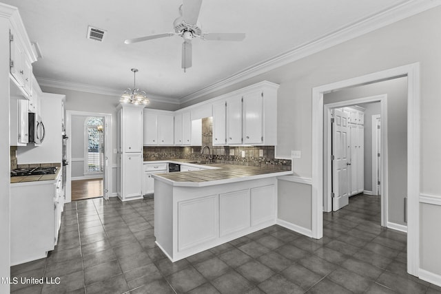 kitchen featuring appliances with stainless steel finishes, kitchen peninsula, hanging light fixtures, white cabinets, and crown molding