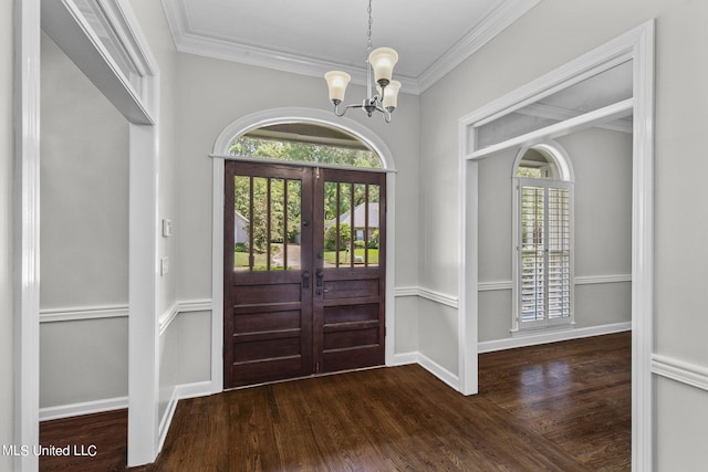 foyer with ornamental molding, a notable chandelier, dark hardwood / wood-style floors, and french doors