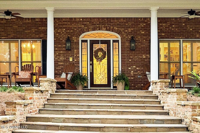 entrance to property featuring brick siding, a ceiling fan, and covered porch