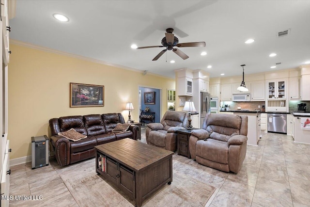 living area with ceiling fan, baseboards, visible vents, and ornamental molding