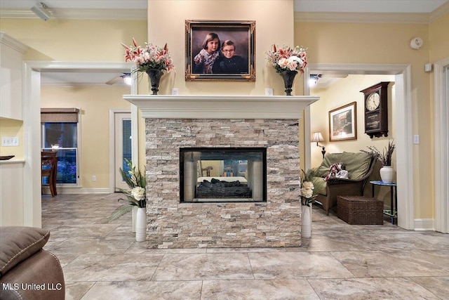 living area with baseboards, crown molding, and a stone fireplace