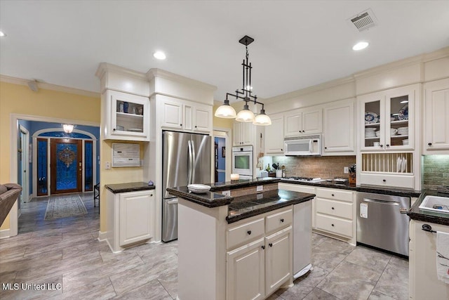 kitchen featuring stainless steel appliances, dark countertops, visible vents, backsplash, and a kitchen island