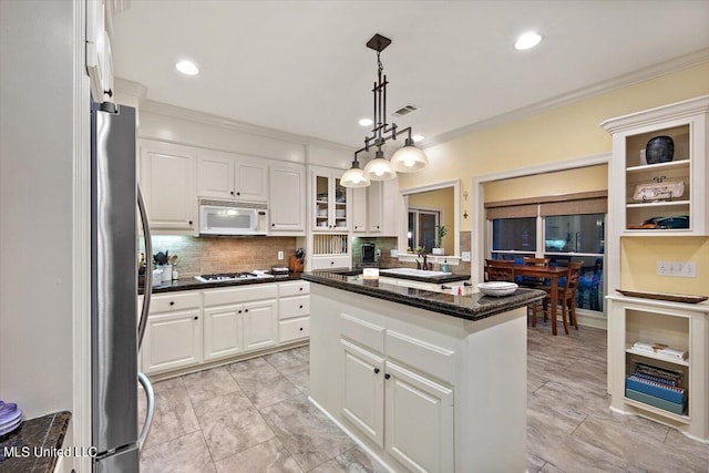kitchen featuring crown molding, freestanding refrigerator, white microwave, white cabinets, and a kitchen island