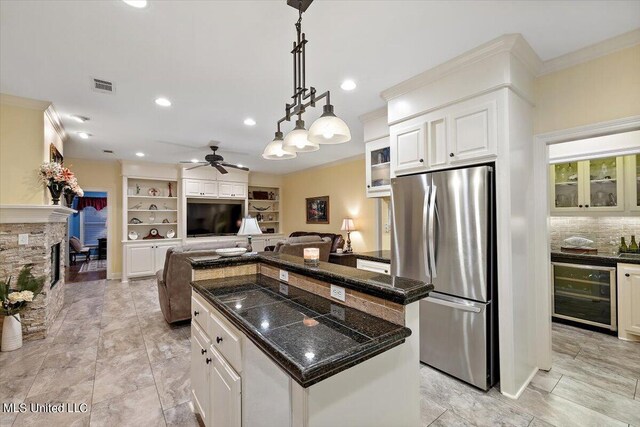 kitchen with a center island, crown molding, beverage cooler, ceiling fan, and freestanding refrigerator