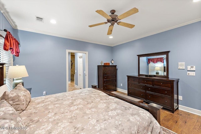 bedroom with wood finished floors, visible vents, baseboards, and ornamental molding