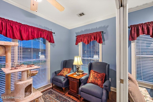 sitting room featuring wood finished floors, ceiling fan, baseboards, ornamental molding, and visible vents