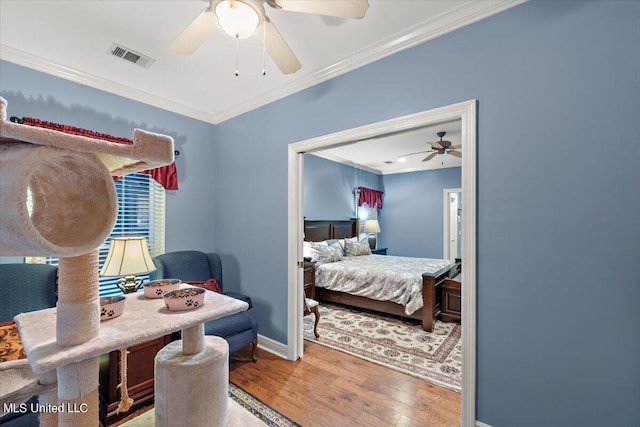 bedroom with visible vents, baseboards, wood finished floors, ceiling fan, and crown molding