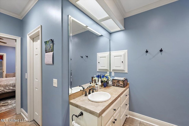ensuite bathroom featuring tile patterned flooring, vanity, ornamental molding, connected bathroom, and baseboards