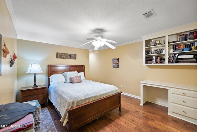 bedroom with built in desk, a textured ceiling, ceiling fan, dark wood-type flooring, and crown molding