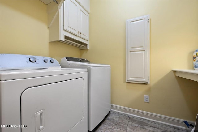 washroom featuring baseboards, washer and clothes dryer, and cabinet space