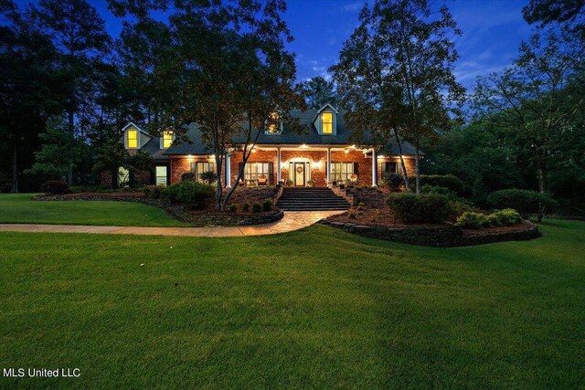 view of front of house with brick siding, a front yard, and covered porch