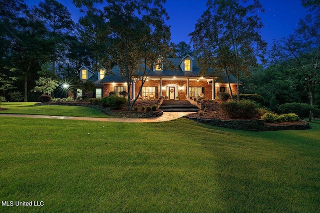 cape cod house featuring a porch and a yard