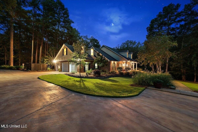 view of front of property featuring concrete driveway, a yard, and a garage