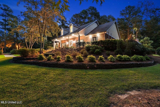 property exterior at twilight featuring brick siding and a yard