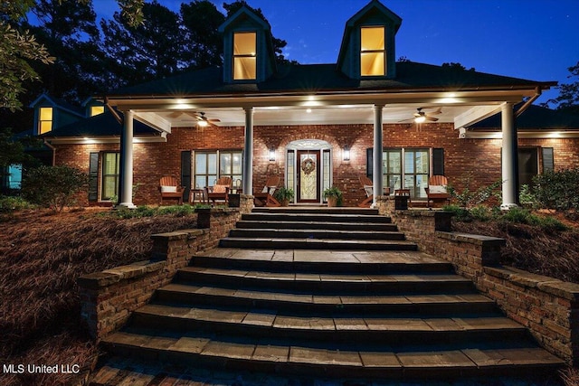 back of house at twilight with brick siding, stairway, a porch, and ceiling fan