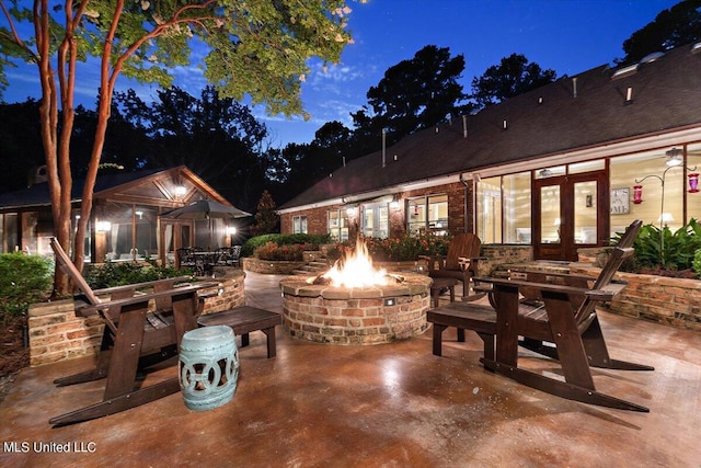 patio at night featuring a fire pit and french doors