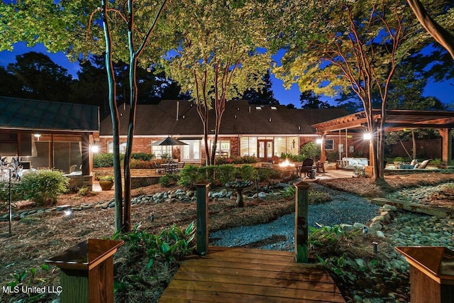 back of house at twilight with a standing seam roof, a patio, and metal roof