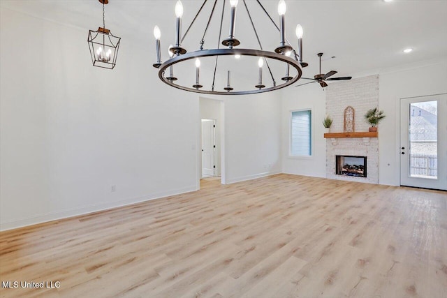 121 Ashby Ridge Dr, Canton, MS 39046 - unfurnished living room featuring a chandelier, light wood finished floors, ceiling fan, baseboards, and a fireplace