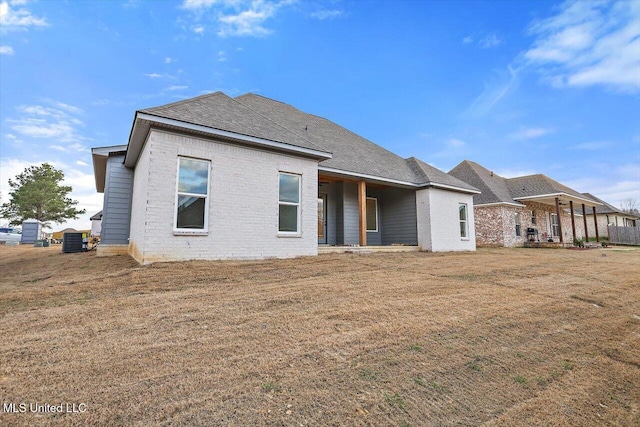 121 Ashby Ridge Dr, Canton, MS 39046 - back of house featuring brick siding, central AC unit, a shingled roof, and a lawn
